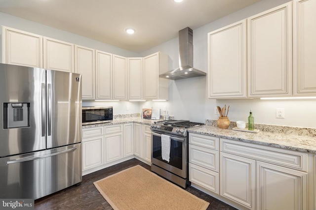 kitchen with light stone countertops, dark wood finished floors, recessed lighting, appliances with stainless steel finishes, and wall chimney exhaust hood