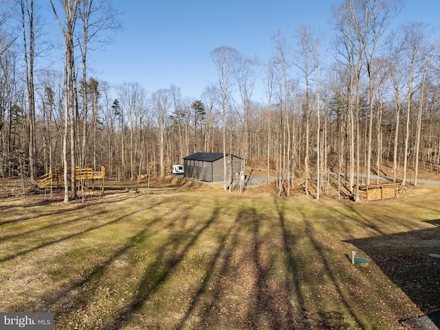 view of yard featuring an outbuilding, a forest view, and driveway