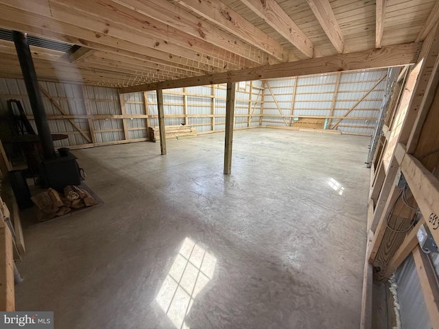 interior space featuring a wood stove, metal wall, and concrete floors