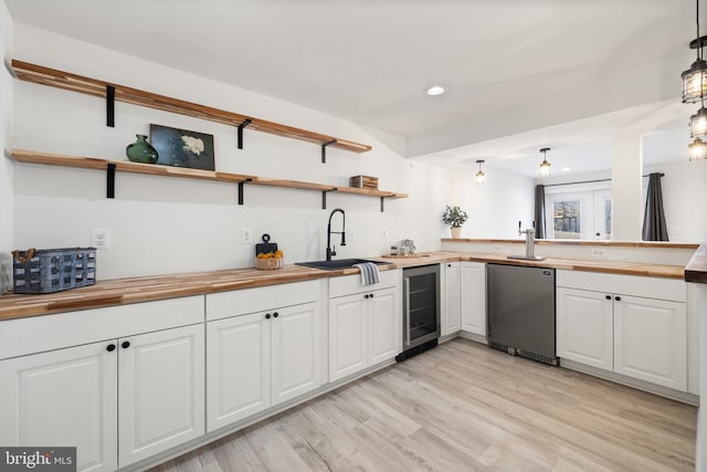 kitchen featuring beverage cooler, a sink, open shelves, light wood-style floors, and butcher block counters