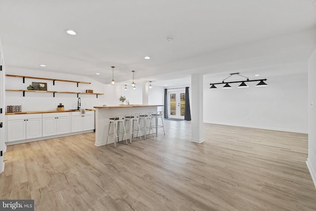 kitchen with open floor plan, butcher block counters, light wood-type flooring, recessed lighting, and white cabinetry