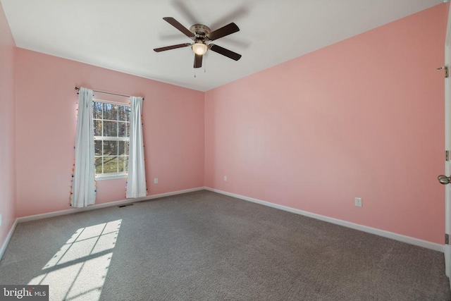 carpeted spare room with visible vents, baseboards, and a ceiling fan