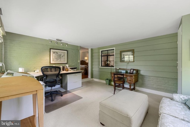 office area featuring rail lighting, baseboards, carpet, and brick wall