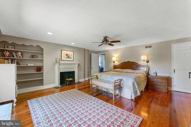 bedroom featuring visible vents, a fireplace with flush hearth, and wood finished floors