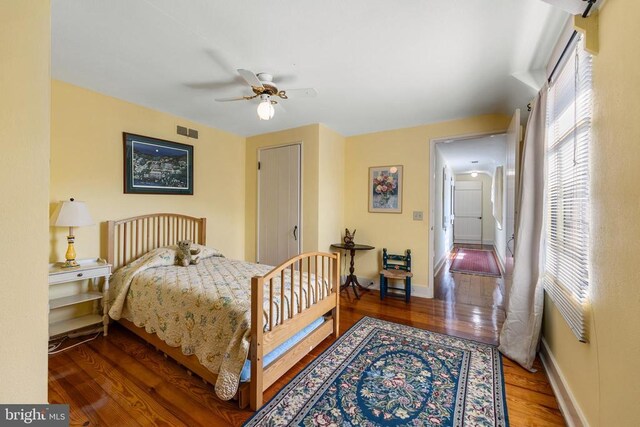 bedroom featuring baseboards, visible vents, multiple windows, and wood finished floors