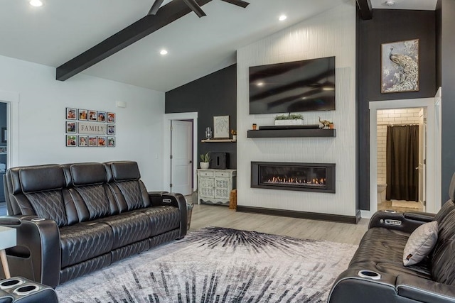 living room featuring lofted ceiling with beams, ceiling fan, a fireplace, and light hardwood / wood-style flooring