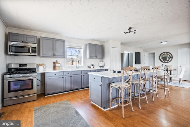 kitchen featuring appliances with stainless steel finishes, a breakfast bar, sink, a center island, and light hardwood / wood-style floors