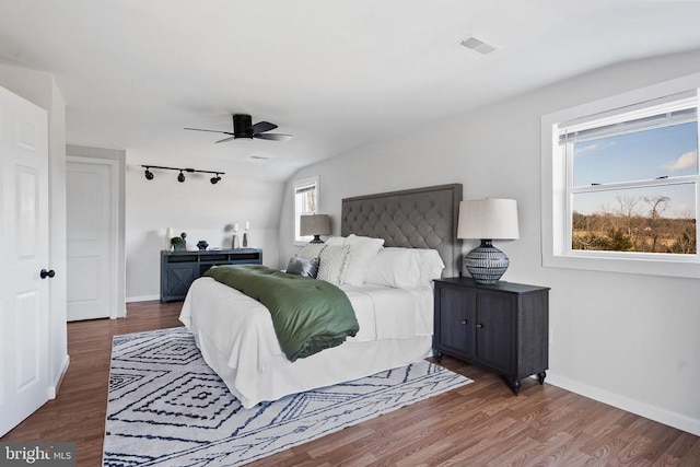 bedroom featuring rail lighting, dark hardwood / wood-style floors, and ceiling fan