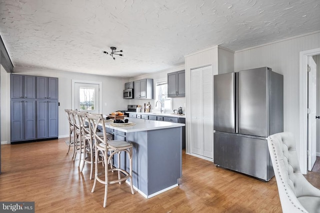 kitchen featuring gray cabinets, a breakfast bar, a center island, stainless steel appliances, and light wood-type flooring