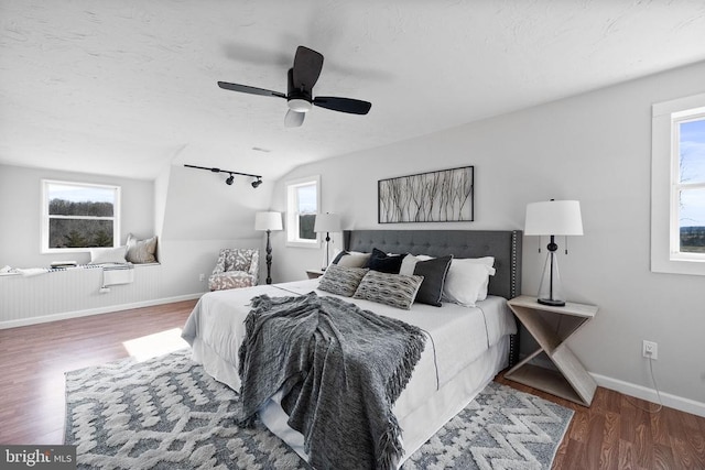 bedroom featuring hardwood / wood-style flooring, track lighting, a textured ceiling, and ceiling fan