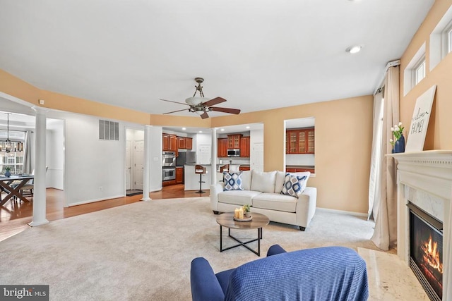 living room with a healthy amount of sunlight, visible vents, a fireplace, and ornate columns