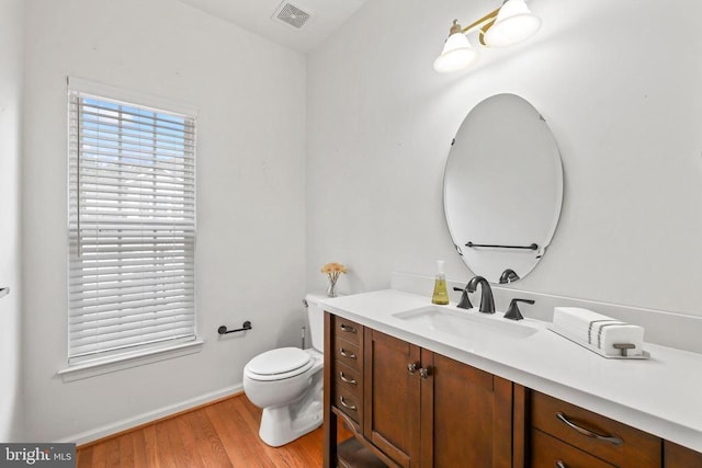 bathroom featuring toilet, wood finished floors, vanity, visible vents, and baseboards