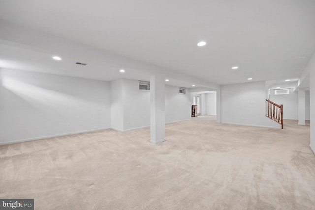 finished below grade area featuring recessed lighting, visible vents, light carpet, baseboards, and stairs