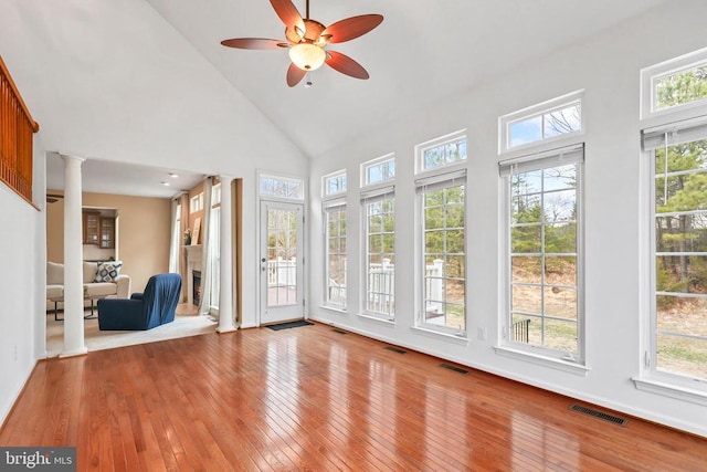 unfurnished sunroom featuring a fireplace, decorative columns, visible vents, and a healthy amount of sunlight