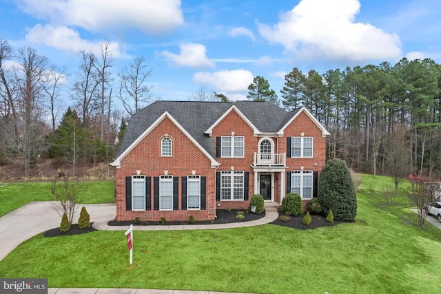 colonial house featuring a front lawn, a shingled roof, and brick siding