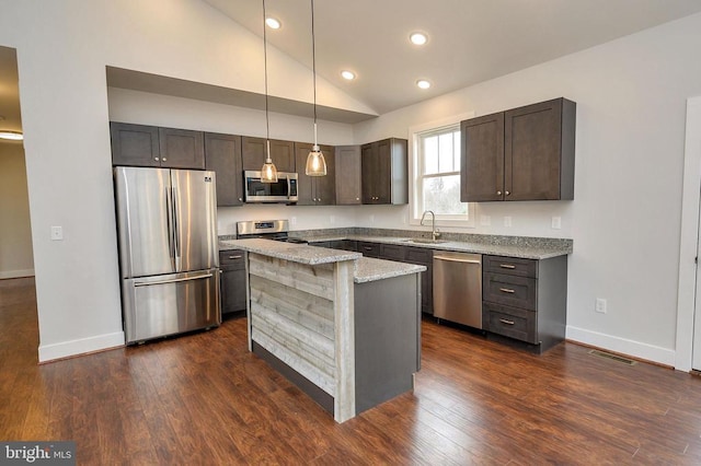 kitchen featuring dark brown cabinetry, stainless steel appliances, a kitchen island, hanging light fixtures, and light stone countertops