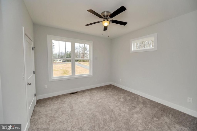 unfurnished room with light colored carpet, visible vents, ceiling fan, and baseboards