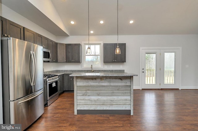 kitchen featuring light stone counters, dark wood-style flooring, appliances with stainless steel finishes, a center island, and decorative light fixtures