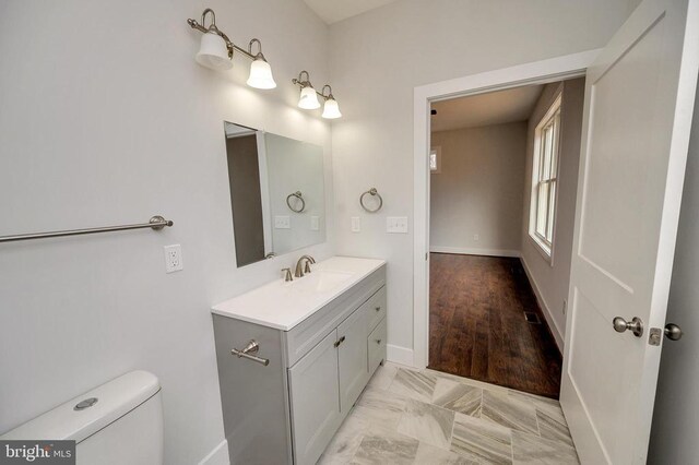 bathroom featuring marble finish floor, vanity, toilet, and baseboards