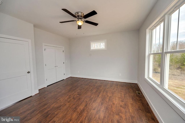 unfurnished bedroom featuring baseboards, visible vents, ceiling fan, dark wood-type flooring, and a closet