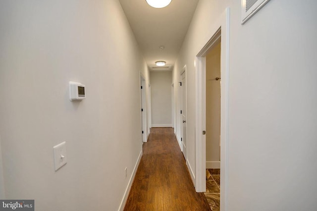 hallway with dark wood-type flooring and baseboards