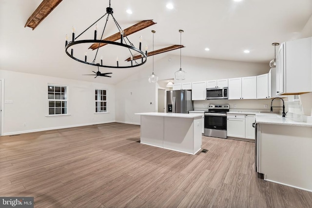 kitchen with a kitchen island, decorative light fixtures, sink, white cabinets, and stainless steel appliances