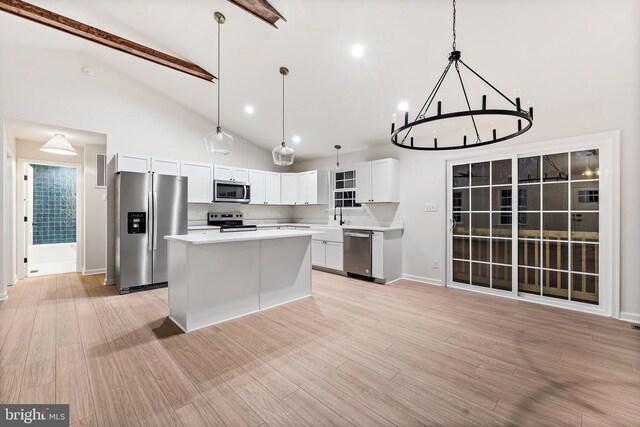 kitchen featuring stainless steel appliances, a center island, hanging light fixtures, and white cabinets