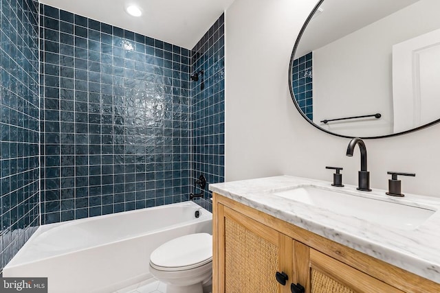 full bathroom featuring tiled shower / bath, vanity, and toilet