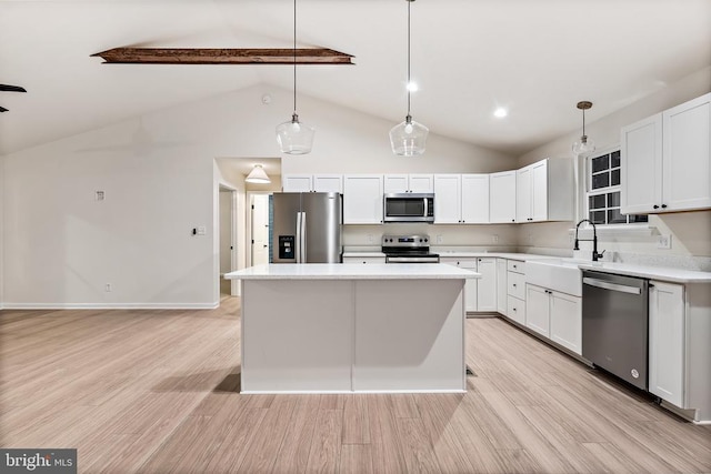 kitchen featuring stainless steel appliances, a center island, hanging light fixtures, and white cabinets