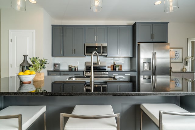 kitchen featuring tasteful backsplash, a breakfast bar, dark stone countertops, stainless steel appliances, and a sink
