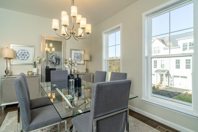 dining room featuring baseboards, wood finished floors, visible vents, and a chandelier