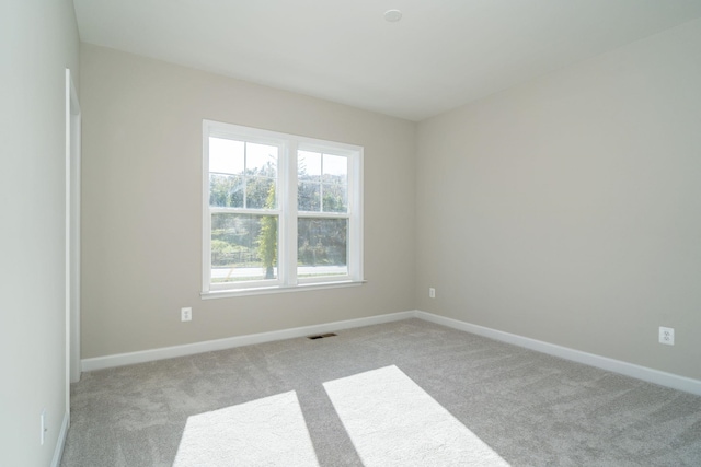 empty room featuring visible vents, baseboards, and light colored carpet