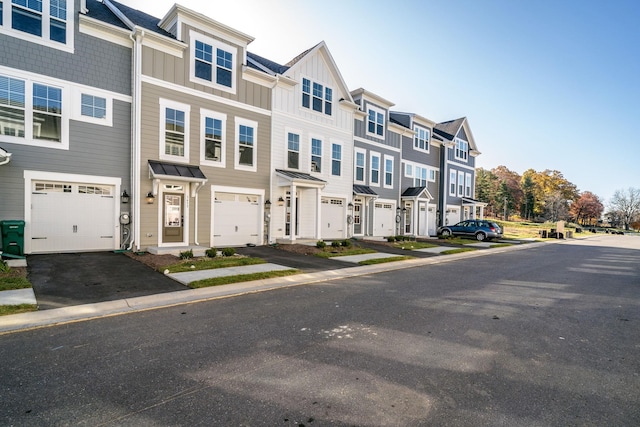 townhome / multi-family property featuring board and batten siding, aphalt driveway, a garage, and a residential view