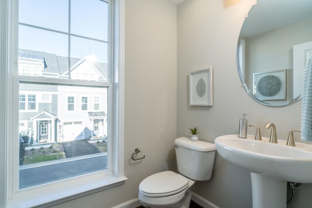 half bathroom with a sink, baseboards, and toilet