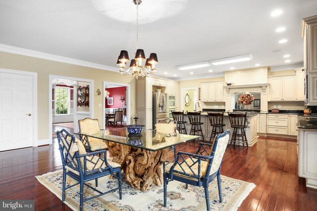 dining space featuring dark hardwood / wood-style flooring, a notable chandelier, crown molding, and sink