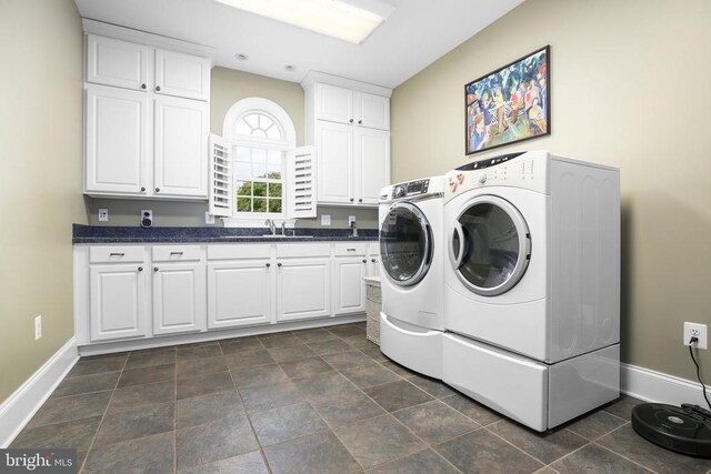 clothes washing area with cabinets, washing machine and clothes dryer, and sink