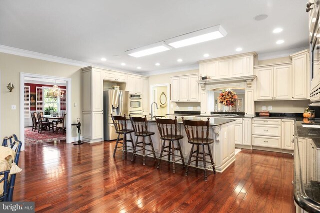 kitchen featuring stainless steel refrigerator with ice dispenser, cream cabinets, a breakfast bar, and an island with sink