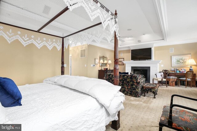 carpeted bedroom with ornamental molding and a tray ceiling