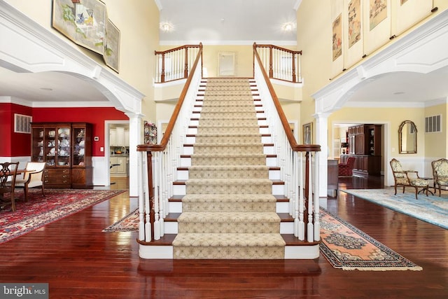 stairway with ornamental molding, wood-type flooring, and ornate columns