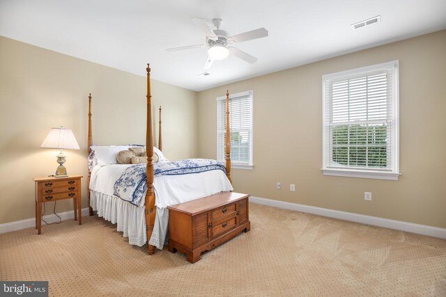 bedroom featuring multiple windows, light carpet, and ceiling fan