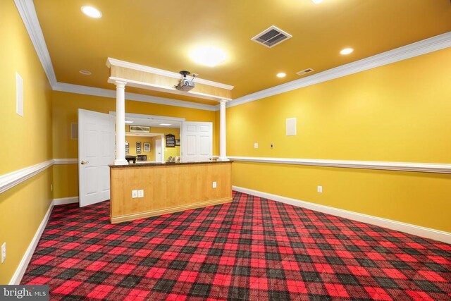 interior space featuring dark carpet, ornamental molding, kitchen peninsula, and decorative columns