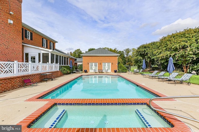 view of swimming pool with an outbuilding, a patio area, and an in ground hot tub