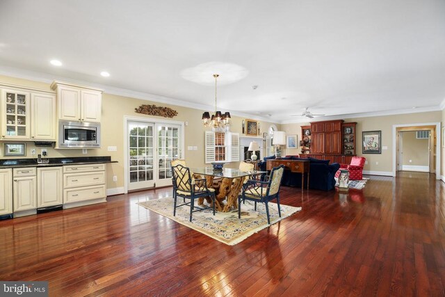 dining room with dark wood-type flooring, crown molding, and ceiling fan with notable chandelier