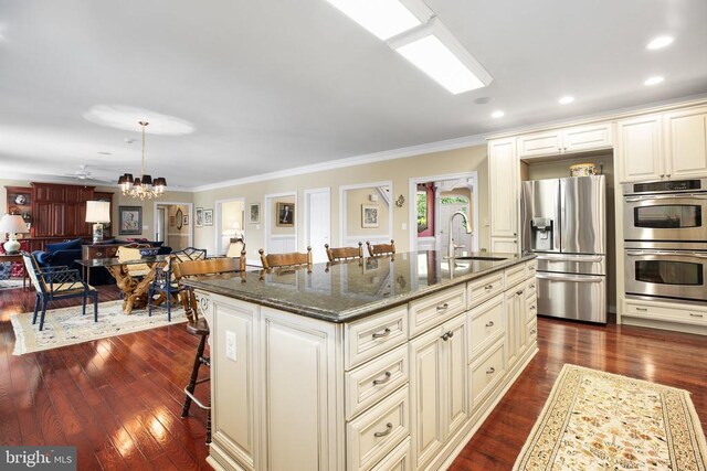 kitchen with sink, a breakfast bar, a kitchen island with sink, hanging light fixtures, and stainless steel appliances