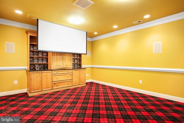 home theater room featuring dark carpet and ornamental molding