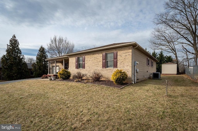 ranch-style house featuring a front yard, an outdoor structure, central AC, and brick siding