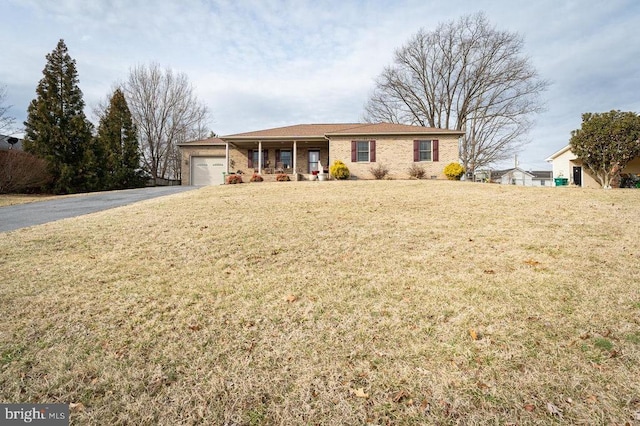 ranch-style home featuring an attached garage, aphalt driveway, and a front yard