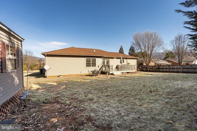 rear view of property with a deck, a lawn, and fence