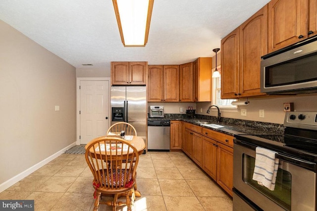 kitchen with visible vents, brown cabinetry, stainless steel appliances, a sink, and light tile patterned flooring