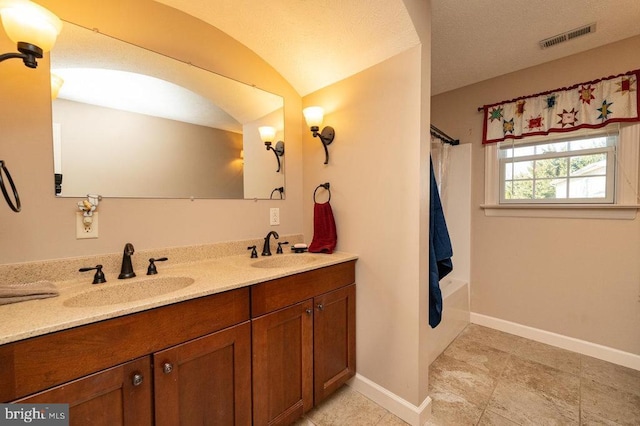 bathroom with double vanity, a sink, visible vents, and baseboards